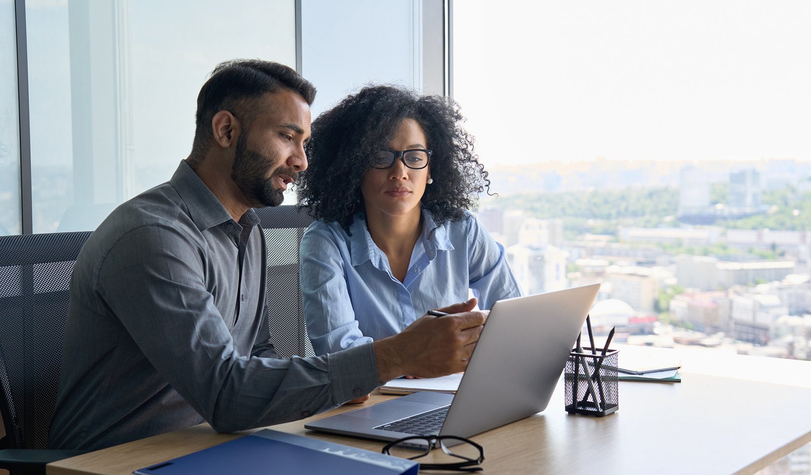 man and woman sitting at desk looking at computer